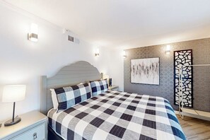 A bedroom with a checkered bedspread, a nightstand with a lamp, and a wall-mounted artwork. - The Waves: unit A - Beach Duplex, Full Kitchen (South Padre Island)
