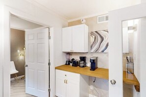 A compact kitchen with white cabinetry, a wooden countertop, and a coffee maker. - The Waves: unit A - Beach Duplex, Full Kitchen (South Padre Island)