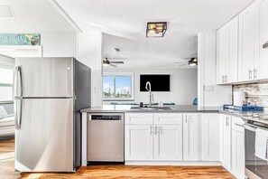 A modern kitchen with white cabinets, stainless steel appliances, and a dishwasher. - Redicare Resort - Upstairs (Galveston)