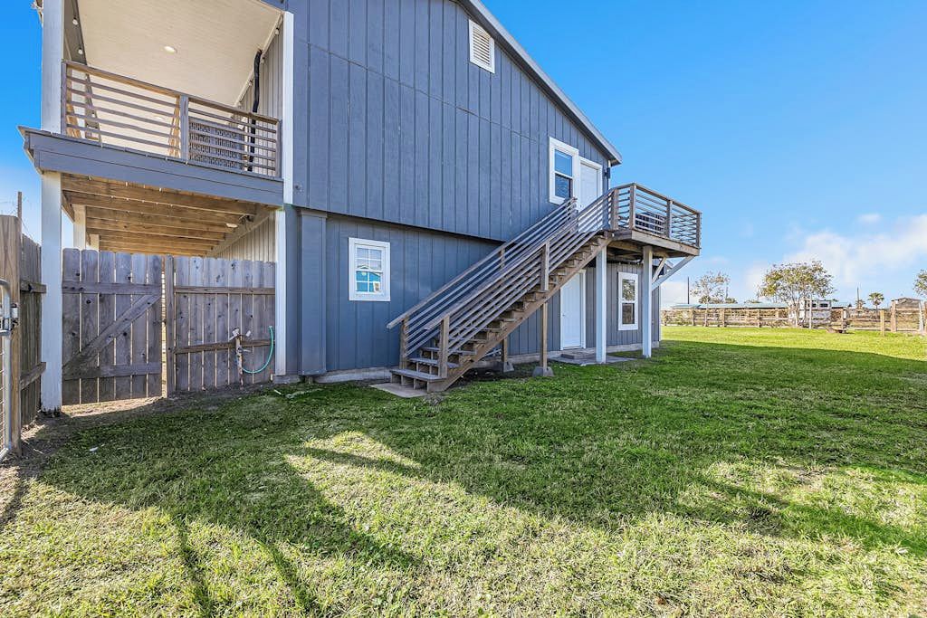 A two-story house with a wooden deck, a staircase, and a fenced yard.