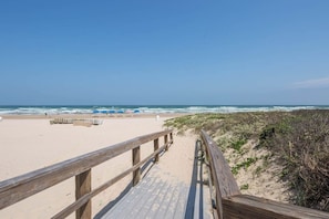 A wooden boardwalk leading to a sandy beach with a clear sky. - Sapphire Condominiums #806 (South Padre Island)