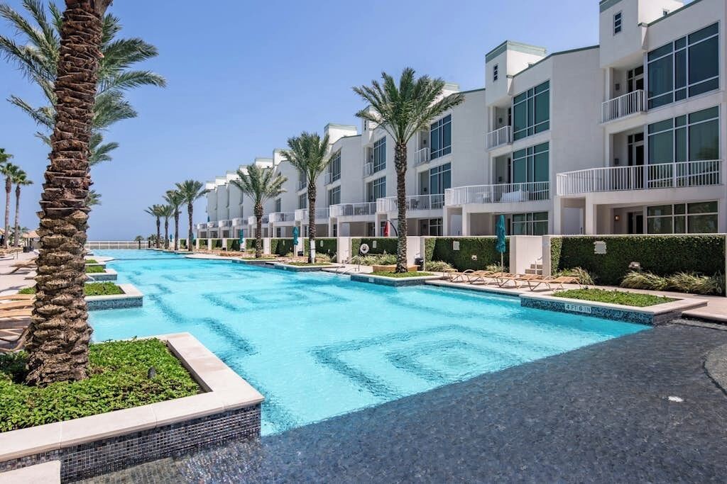 Un hotel con piscina, palmeras y arquitectura moderna.