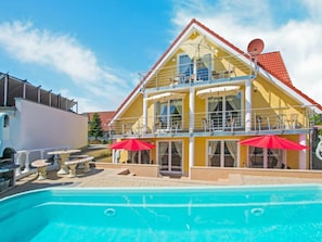 A two-story hotel with a swimming pool, outdoor seating, and satellite dishes. - Holiday Apartment With 1 Bedroom (Heringsdorf)