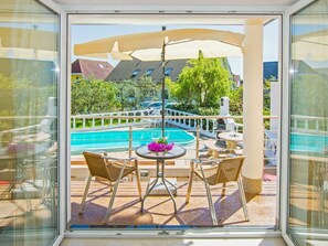 A balcony with a view of a swimming pool, outdoor furniture, and a pergola. - Holiday Apartment With 1 Bedroom (Heringsdorf)