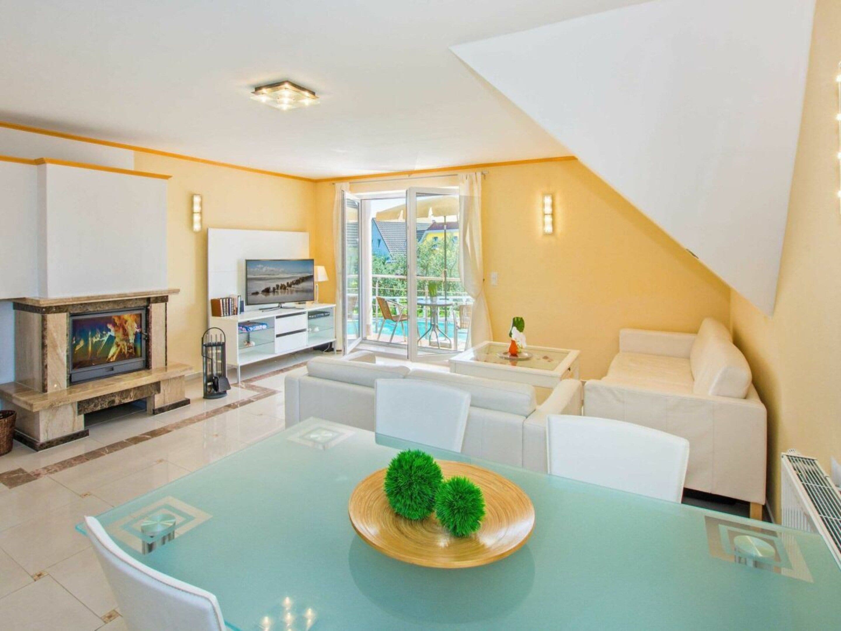 Una sala de estar moderna con chimenea, televisor y comedor con mesa de vidrio.