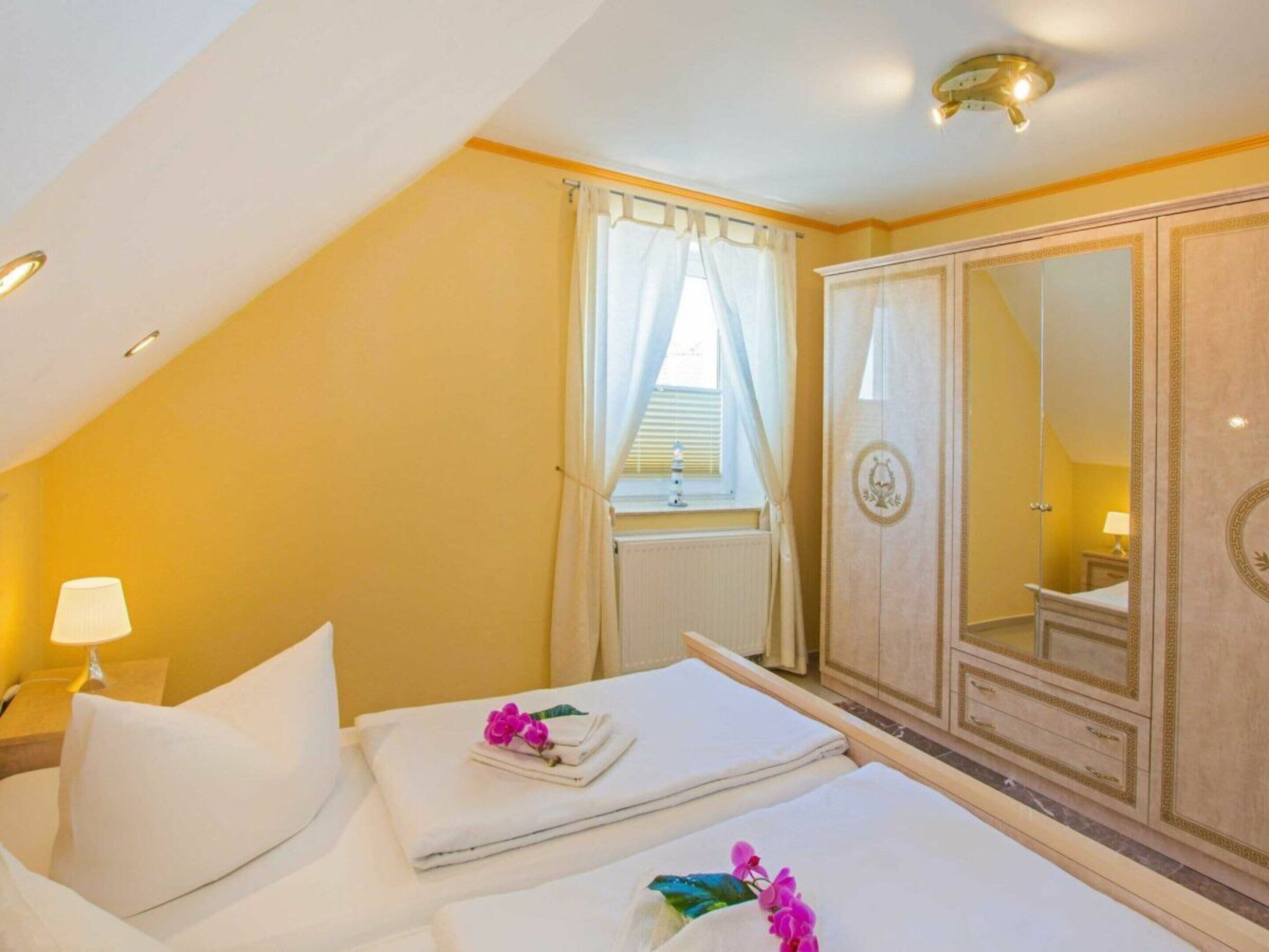 Une chambre d’hôtel avec un lit, une table de chevet, une lampe, une armoire et une fenêtre avec des rideaux.
