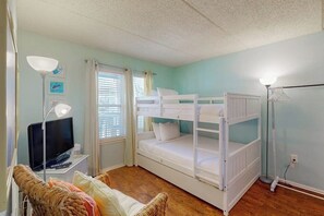 A room with bunk beds, a television, a lamp, and a window with curtains. - Surfside II Unit 309 (South Padre Island)