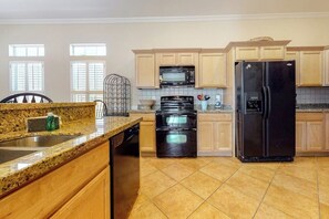 A kitchen with granite countertops, a dishwasher, a double oven, a microwave, and a black refrigerator. - Lantana Oasis - Private Pool, Hot Tub & Dogs OK (South Padre Island)