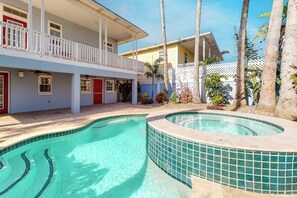 A swimming pool with a curved design, a covered balcony, and a building with a white railing. - Lantana Oasis - Private Pool, Hot Tub & Dogs OK (South Padre Island)