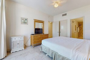 A bedroom with a bed, dresser, mirror, and a door leading to another room. - Sunchase IV #715 - Gulf Views, Pools & Hot Tub (South Padre Island)