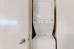 A white washing machine in a room with a door. - Sunchase IV #715 - Gulf Views, Pools & Hot Tub (South Padre Island)