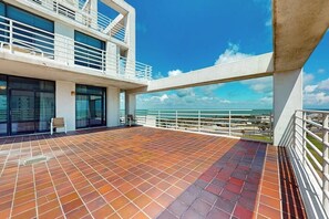 Una terraza en la azotea con vista al océano, que cuenta con piso de baldosas y barandilla.