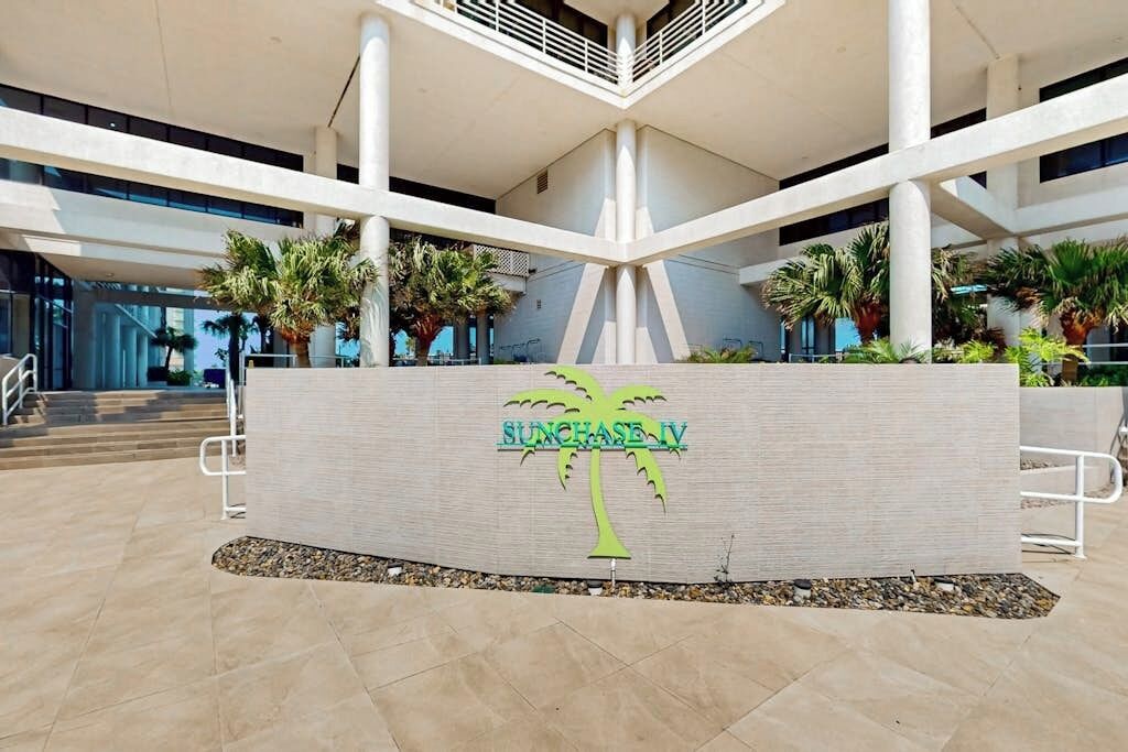 A modern building with a central atrium, palm trees, and a sign reading 'SUNCHASE IV'.