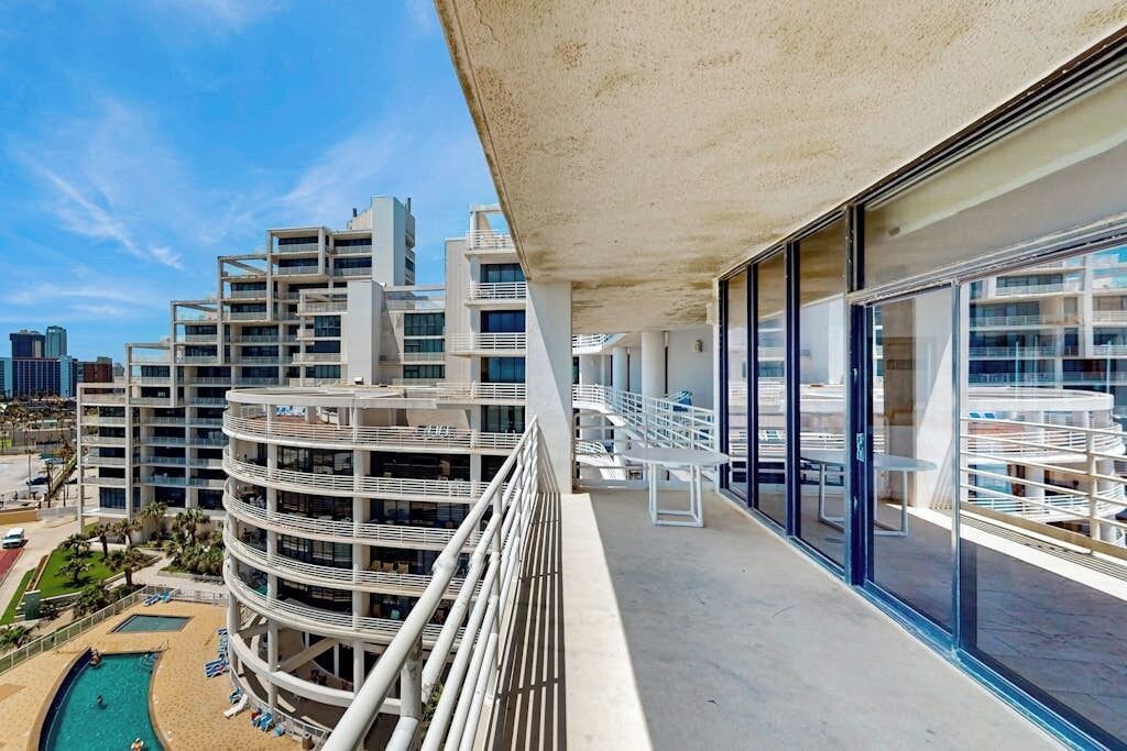 Un immeuble de grande hauteur doté de nombreux balcons, d’un espace piscine et offrant une vue sur le paysage urbain.