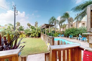 A backyard with a swimming pool, wooden deck, and outdoor furniture. - Butterfly Vine Escape Beach House (South Padre Island)