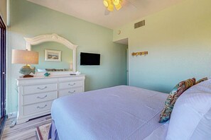 Ein Schlafzimmer mit einem Bett, einem Schminktisch, einem Fernseher und einem Deckenventilator.