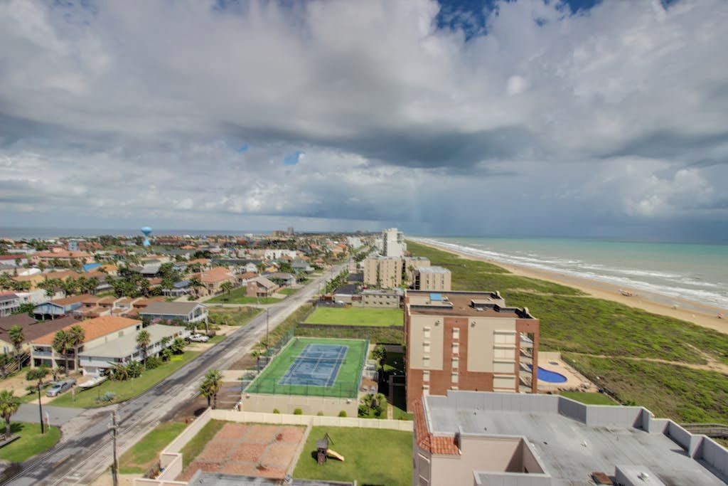 A coastal residential area with a beach, houses, and a tennis court.