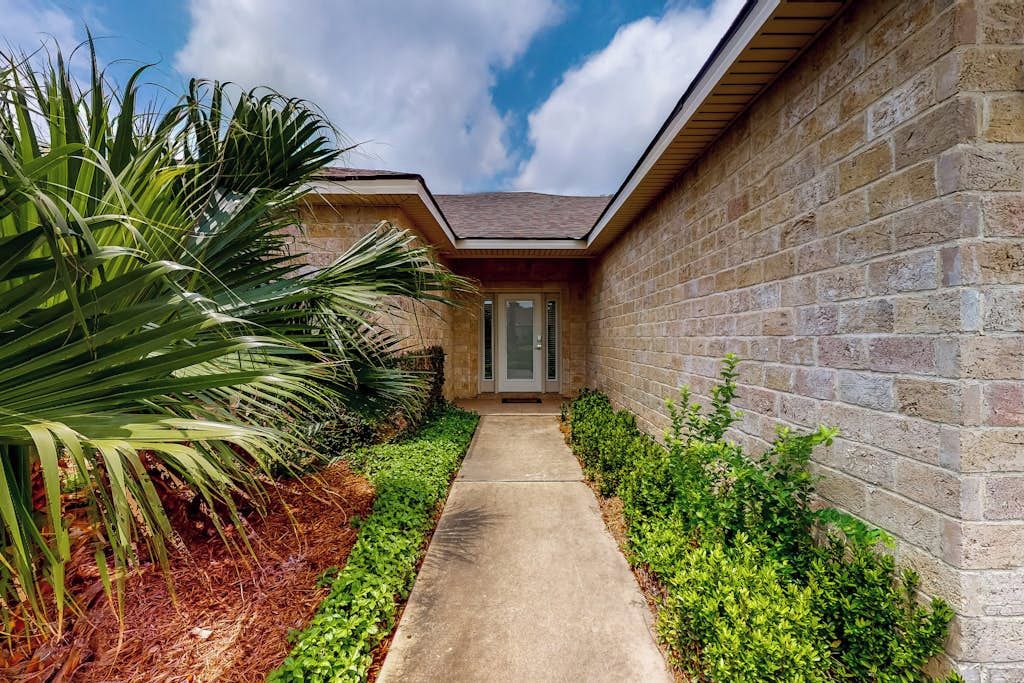 A pathway leading to a house with a brick exterior and a door.