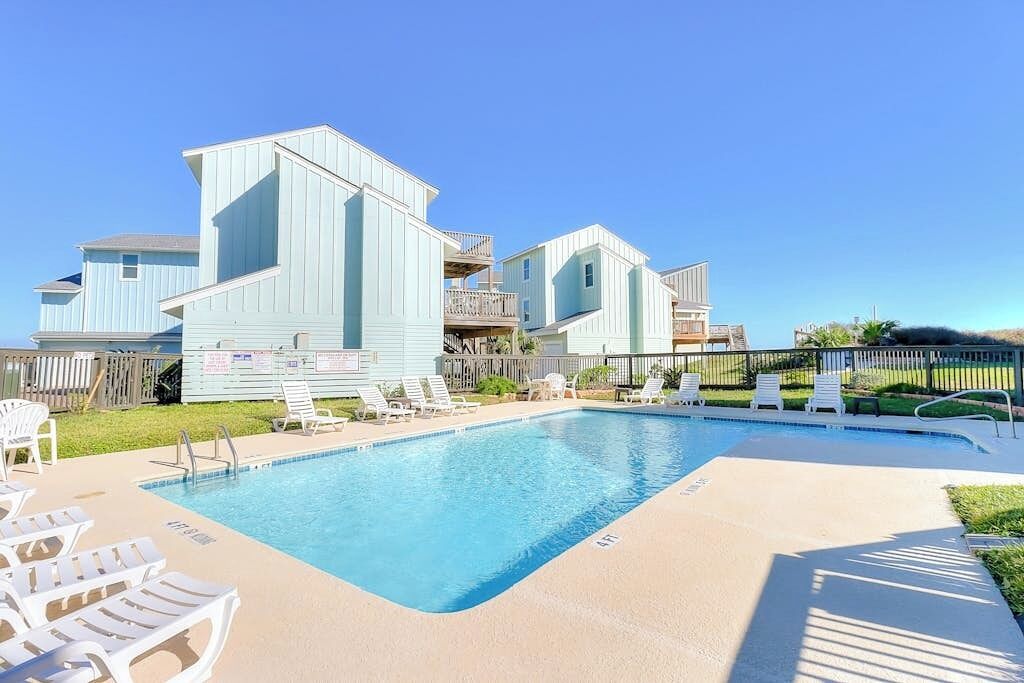 A swimming pool with lounge chairs and a building with a balcony.