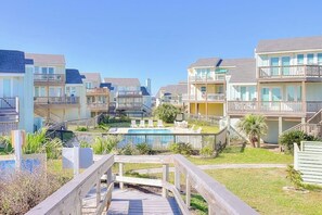 A beachfront residential area with multiple two-story houses, a swimming pool, and a wooden boardwalk. - Rock The Boat - Gulf Views, Deck & Dogs OK (Port Aransas)