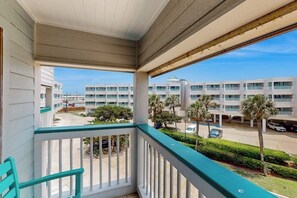 A balcony with a view of a parking lot and a building with multiple floors. - Seawall Getaway - Pool, Balcony, Walk to Beach (Galveston)