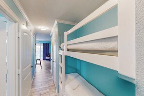 A narrow hallway with bunk beds on one side and a door leading to another room. - Seawall Getaway - Pool, Balcony, Walk to Beach (Galveston)