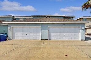 Un bâtiment à deux étages avec une entrée de garage, un ciel dégagé et un palmier en arrière-plan.