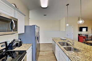 Eine moderne Küche mit Edelstahlgeräten, Granit-Arbeitsplatten und einer zentralen Kochinsel mit Spüle.