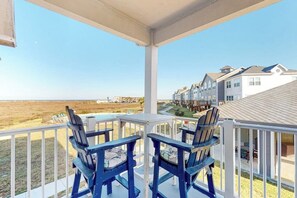 A balcony with two Adirondack chairs overlooking a beach and residential buildings. - Whitecap Retreat - Steps to Beach, Pool & Balcony (Corpus Christi)