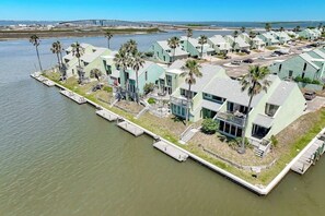 A waterfront property with multiple buildings, docks, and palm trees. - Puente Vista 147 - Waterfront, Pool & Dock (Corpus Christi)