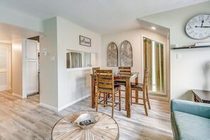A dining area with a wooden table and chairs, a clock on the wall, and a round coffee table. - Puente Vista 147 - Waterfront, Pool & Dock (Corpus Christi)