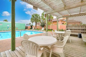 Ein Poolbereich mit überdachter Terrasse, Liegestühlen und einem Tisch.