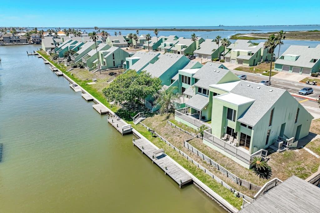 Un quartier résidentiel situé sur la côte, où les maisons sont alignées le long d’un cours d’eau et reliées par des passerelles en bois.