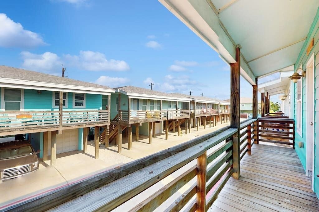 A row of motel rooms with wooden balconies and a covered walkway.