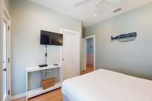 Een slaapkamer met een bed, een witte console, een televisie en een wanddecoratie.