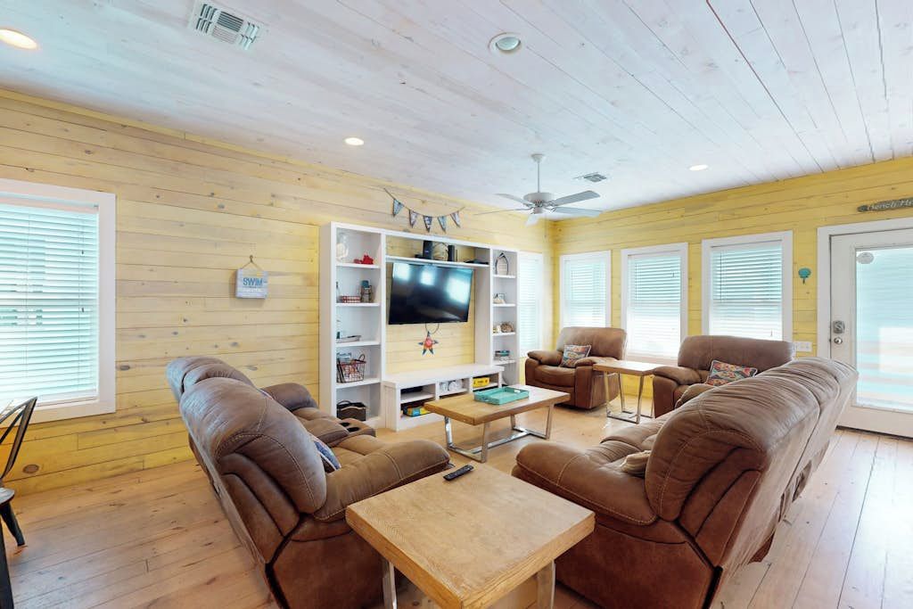 A cozy living room with a television, sofas, and a wooden ceiling.