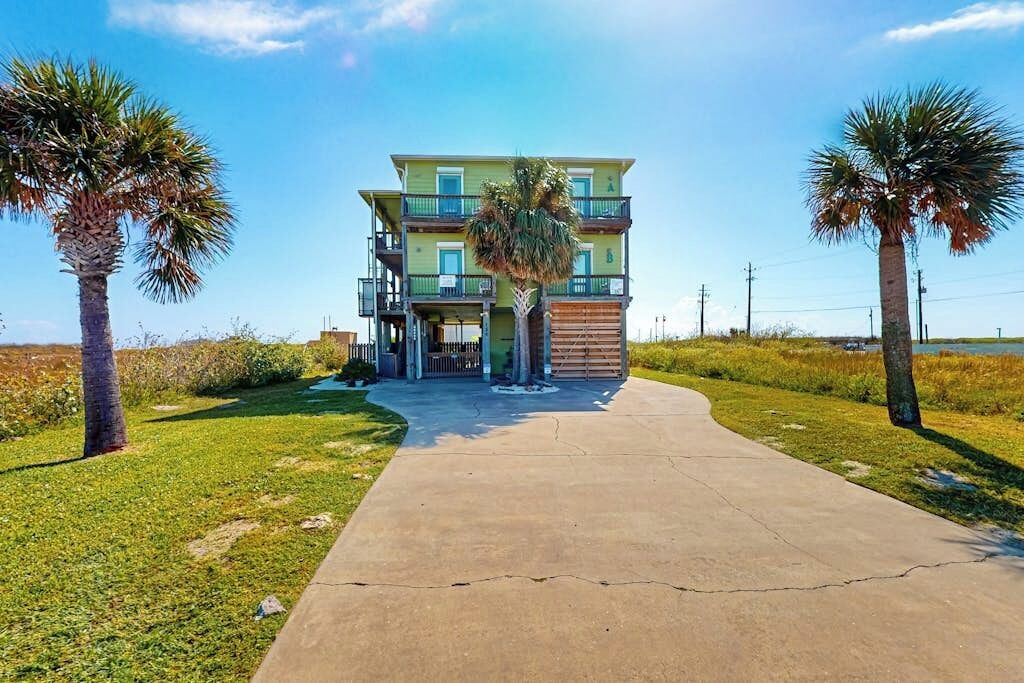 A two-story building with a balcony, surrounded by grass and palm trees.