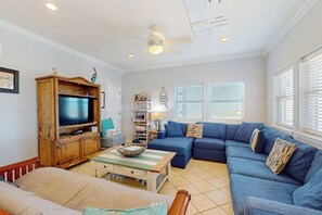 A living room with a television, sofa, and a coffee table. - Gulf Breezes Unit B - Pool, Fenced Yard & Dogs OK (Port Aransas)