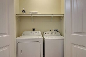 A laundry room with two white front-loading washing machines and a shelf above them. - Nemo Cay 15106 - Pool, Patio, Sleeps 10, Dogs OK (Corpus Christi)