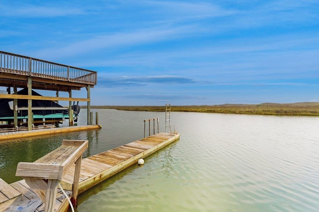 A wooden dock extending into calm water with a building on the left side.