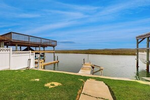 A waterfront property with a dock, a covered area, and a grassy lawn. - Quaint Oasis - Shared Pool & Beach Access (Corpus Christi)