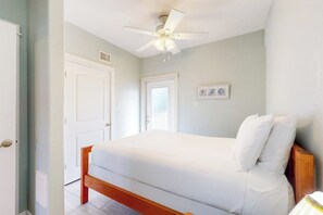 Ein Schlafzimmer mit einem Einzelbett, einem Deckenventilator und einer Tür.