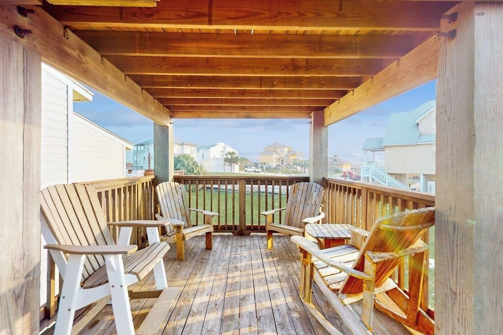 Eine Holzterrasse mit Adirondack-Stühlen und Blick auf ein Wohngebiet.