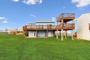 A two-story house with a deck, a garage, and a grassy yard. - Lost Colony Seahorse Villa (Port Aransas)