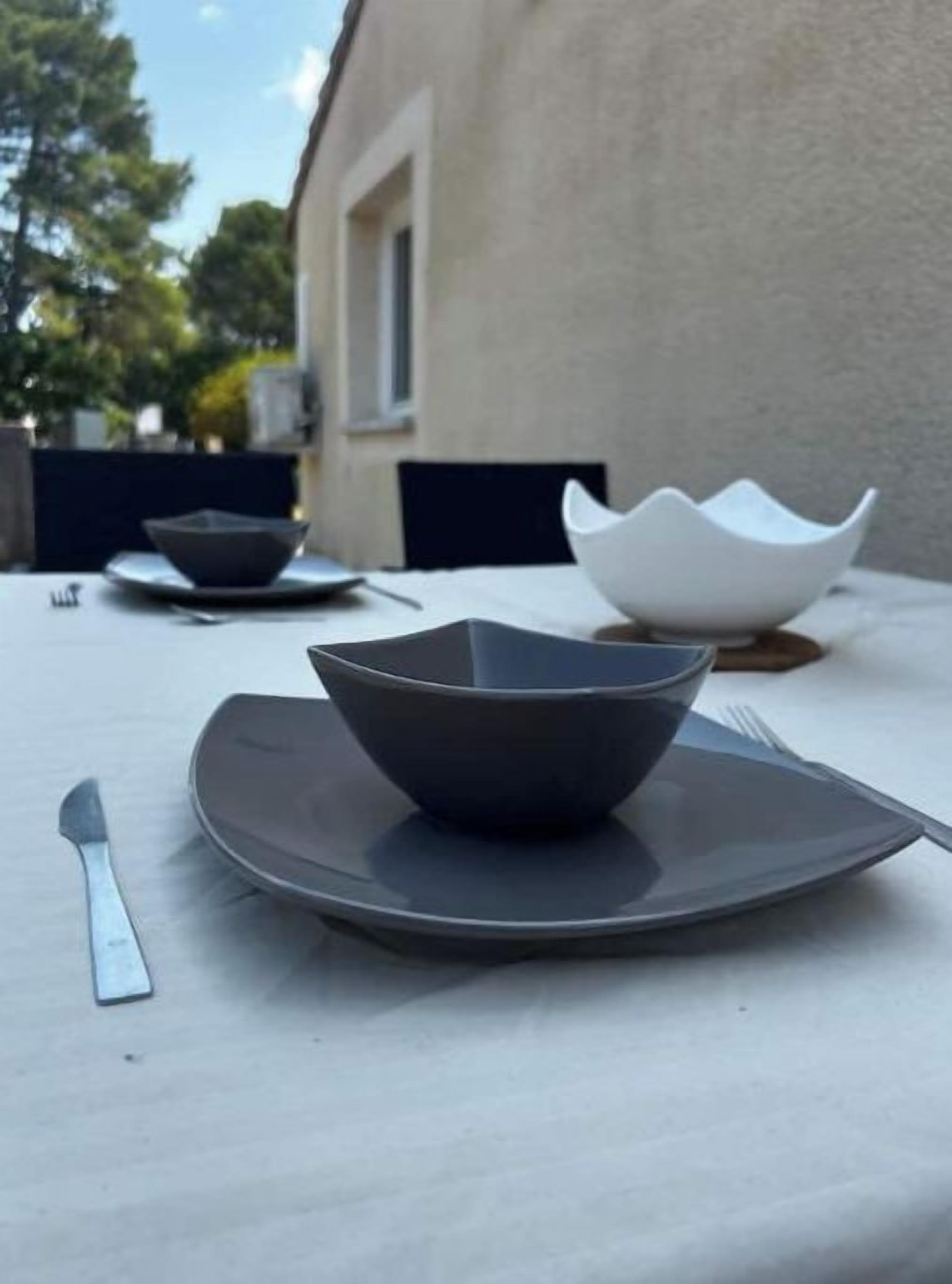 Une table à manger avec une assiette, un bol et des couverts.