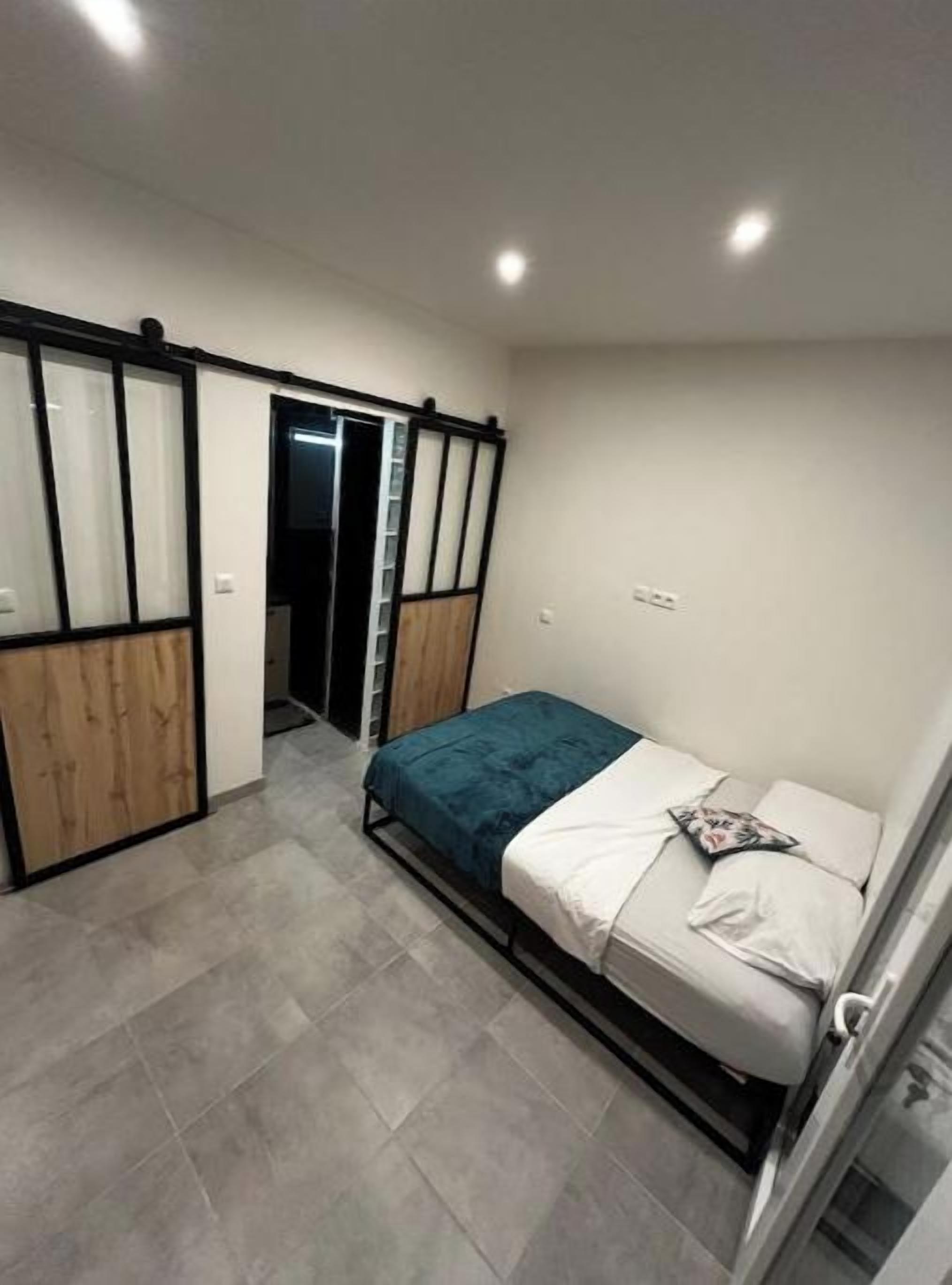A bedroom with a bed, a wardrobe, and a door leading to a bathroom.