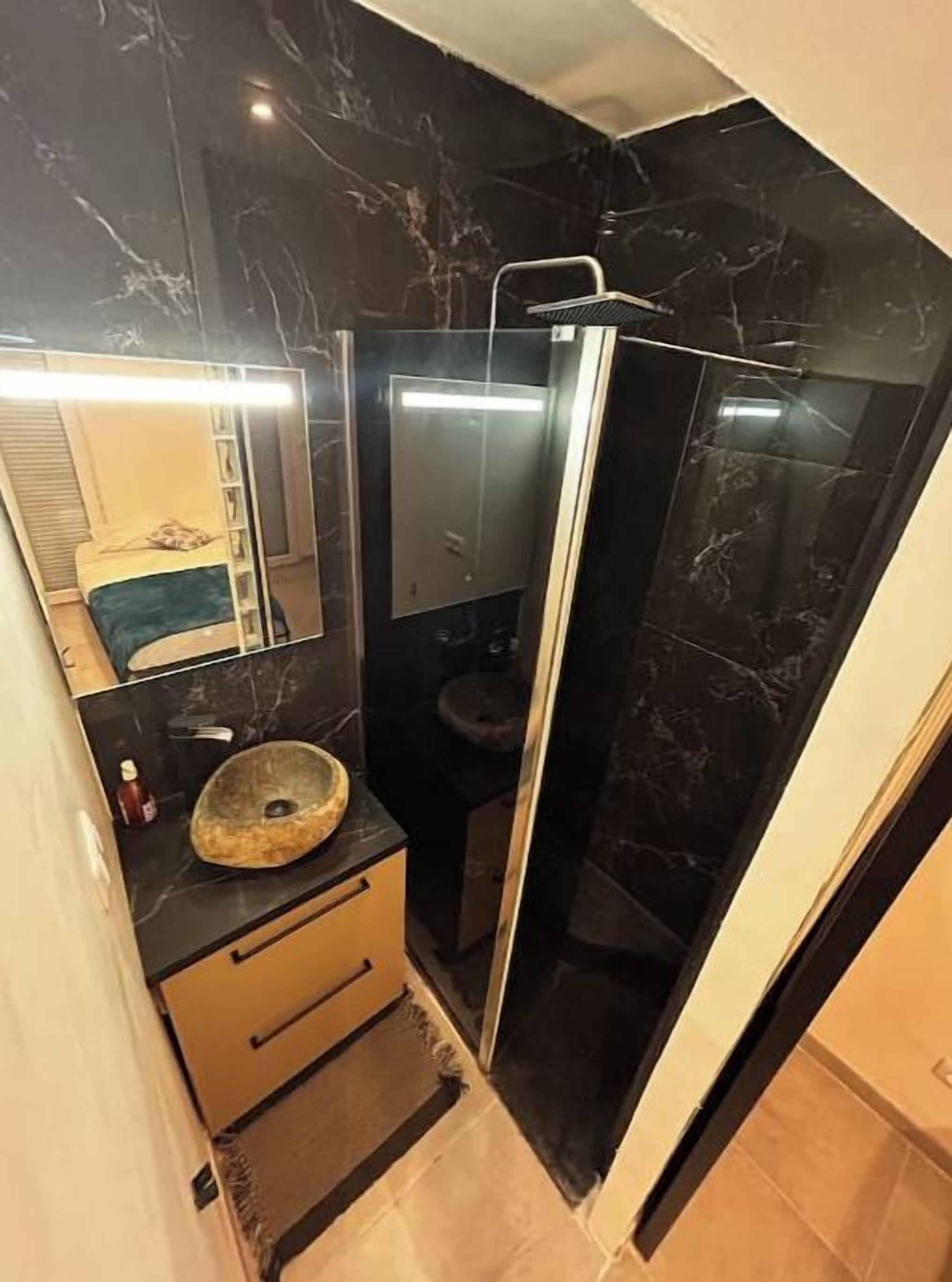 Een badkamer met een marmeren wastafelmeubel, een douche met glazen wanden en een toilet.