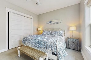 Ein Schlafzimmer mit einem Bett, Nachttischen, einer Bank, einer Tür und einer Wanddekoration.