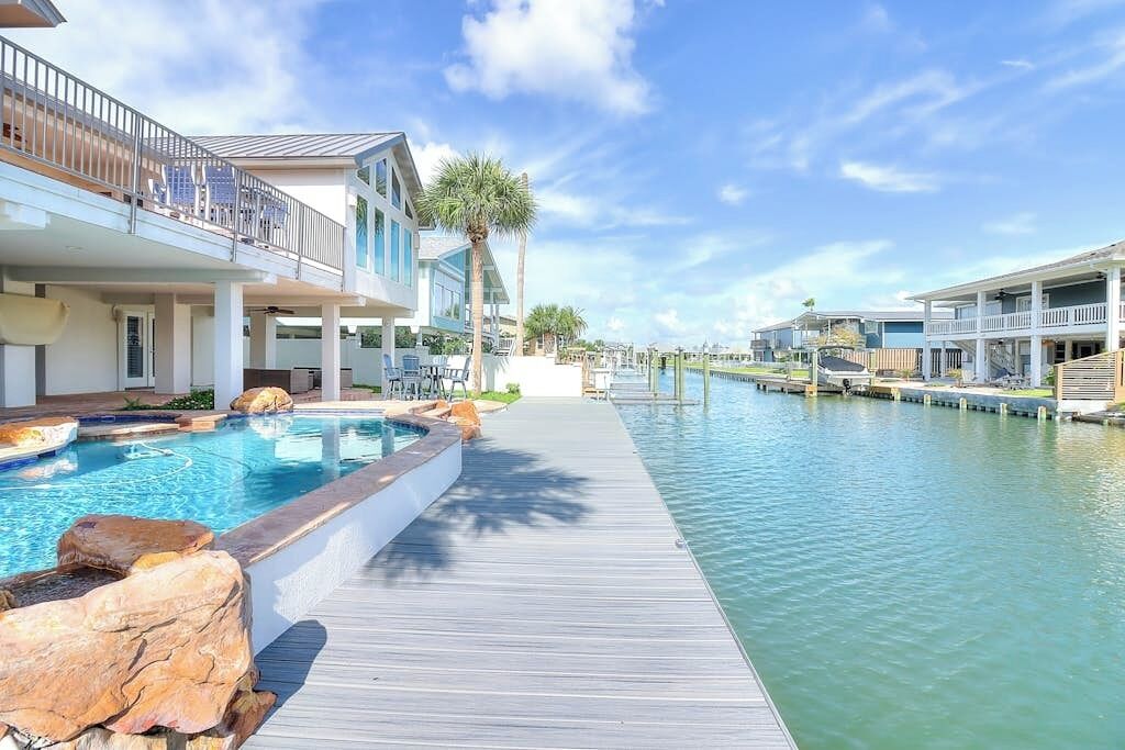 Ein Resort mit Schwimmbad, Holzterrasse und Blick auf das Wasser.