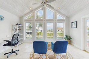 A spacious room with a high ceiling, large windows, a ceiling fan, a desk with a chair, and a view of the outdoors. - Saltwater Solace - Under New Ownership (Rockport)